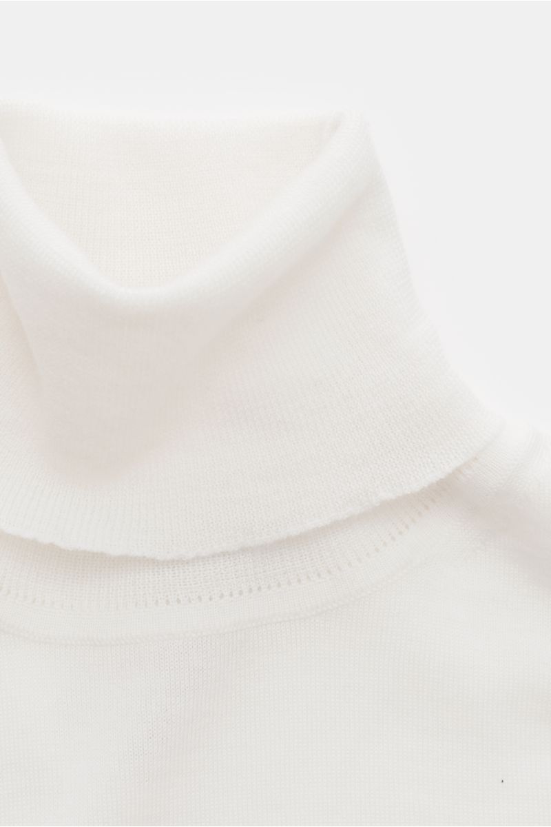 Nahaufnahme von einem cremefarbenen von Braun Merino Rollkragenpullover, superfein gestrickt aus reiner Merinowolle, Slim Fit mit anliegendem Rollkragen und flexiblen Rippbündchen, fotografiert von oben.
