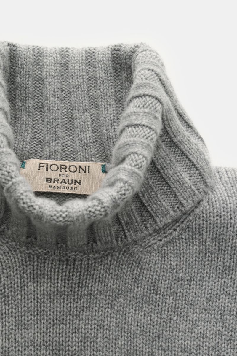 Close-up top-down view of Fioroni Cashmere Rundhalspullover dunkelgrau meliert showcasing ribbed turtleneck and label with fine medium-knit texture.

Description: Souveräne Eleganz in ihrer luxuriösesten Form: Der Rollkragenpullover von FIORONI aus erl