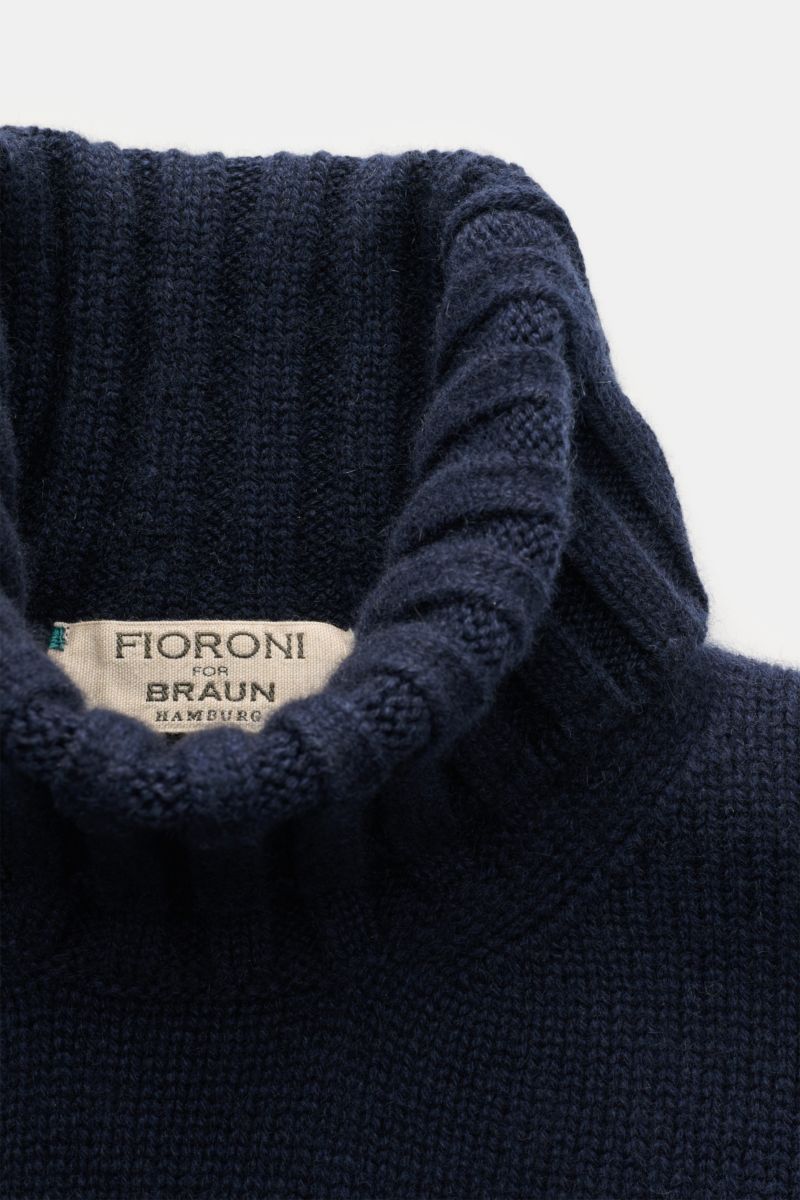 Close-up top-down view of the navy Fioroni Cashmere Rundhalspullover showcasing its ribbed turtleneck and label. Souveräne Eleganz in ihrer luxuriösesten Form: Der Rollkragenpullover von FIORONI aus erlesenem Cashmere vereint meisterhafte italienische 