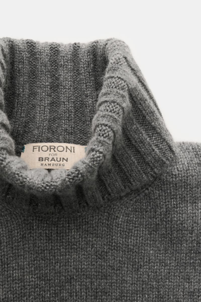 Close-up top-down view of the Fioroni Cashmere Rundhalspullover dunkelgrau meliert showing its ribbed turtleneck and label. Souveräne Eleganz in ihrer luxuriösesten Form: Der Rollkragenpullover von FIORONI aus erlesenem Cashmere vereint meisterhafte it