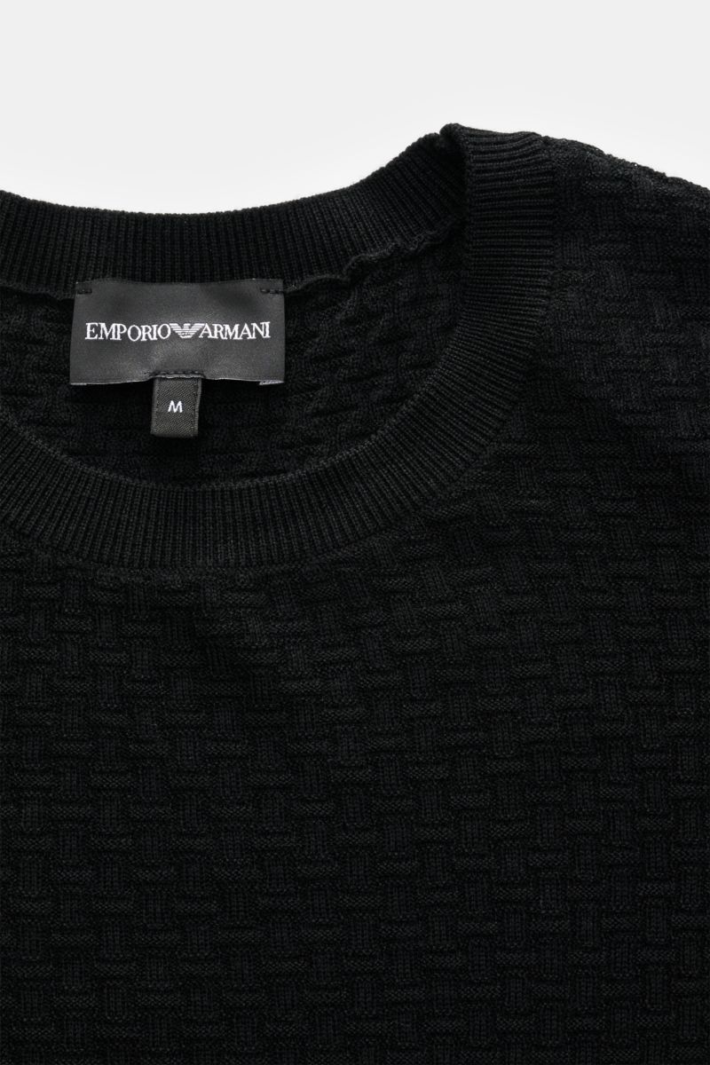 Close-up front view of Emporio Armani Feinstrick-Rundhalspullover schwarz showing fine knit pattern and ribbed round neckline.

Angenehm weich, leicht und modern präsentiert sich dieser fein strukturierte Rundhalspullover von EMPORIO ARMANI aus reiner 