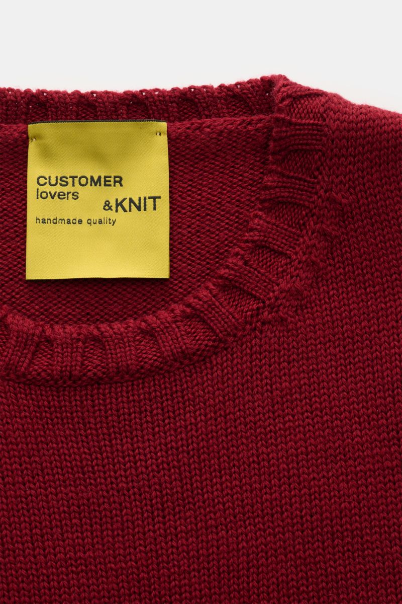 B.F. Knitwear Merino Rundhalspullover dunkelrot aus reine Merinowolle, weicher Griff, mittelgrobes Strickbild, Slim Fit, Rundhalsausschnitt, breite Rippstrick-Bündchen, Nahaufnahme von oben.