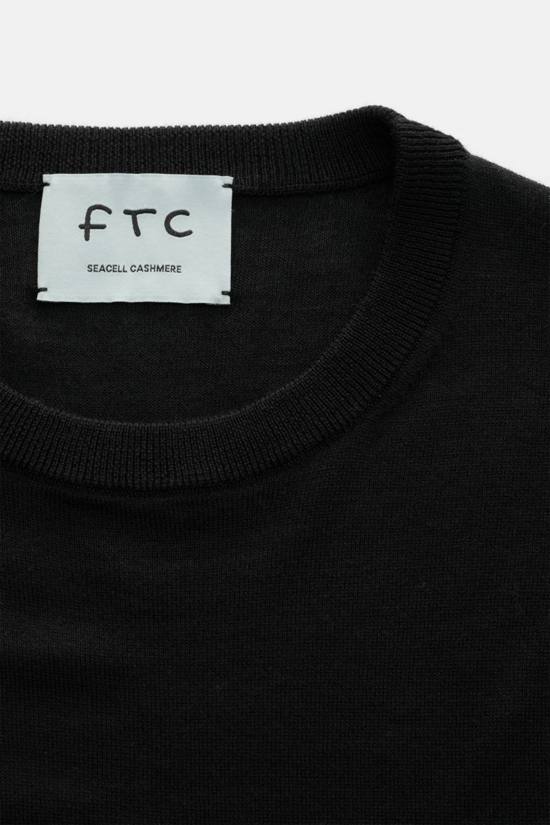 Close-up front view of the FTC Fine knit crew neck jumper black, showing crew neck and label. Blend of cashmere and lyocell, OEKO-TEX® Standard 100 certified, very soft feel, very fine knit, slim fit, crew neck, comfortable ribbed bands.