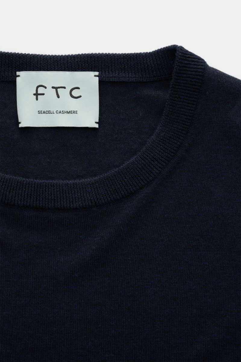 Close-up front view of the navy FTC Fine knit crew neck jumper navy showing the crew neck and label, featuring a blend of cashmere and lyocell, OEKO-TEX® Standard 100 certified, very soft feel, very fine knit, slim fit, crew neck, and comfortable ribbed b