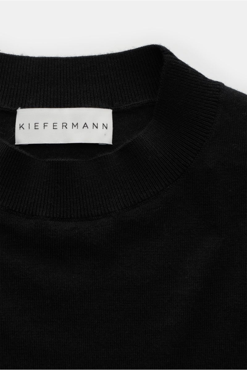 Close-up front view of the Kiefermann Merino Feinstrick-Pullover schwarz showing the high round neckline and label, made of reine Merinowolle, superweicher Griff, sehr feines Strickbild, Slim Fit, hoher Rundhalsausschnitt, elastische Ärmelabschlüsse.