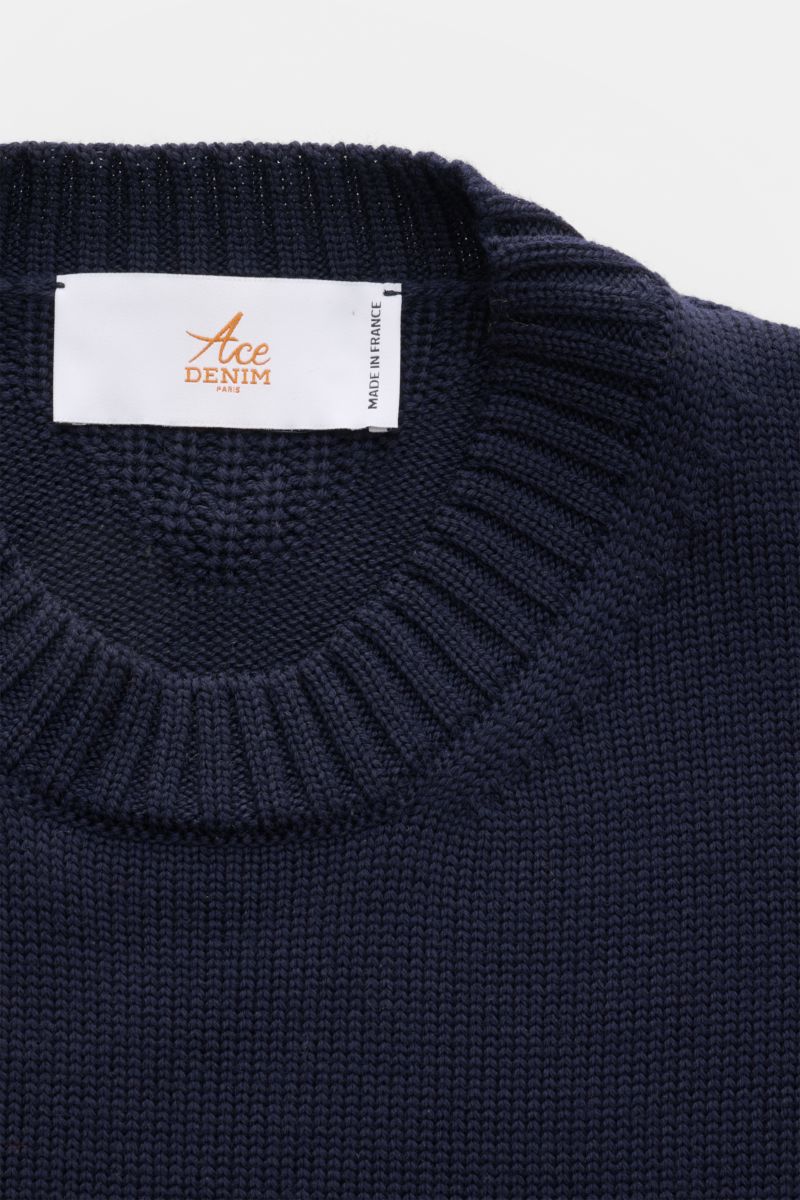 Close-up top view of Ace Denim Merino crew neck jumper navy showing ribbed crew neck collar and white label with orange logo, made in France.


