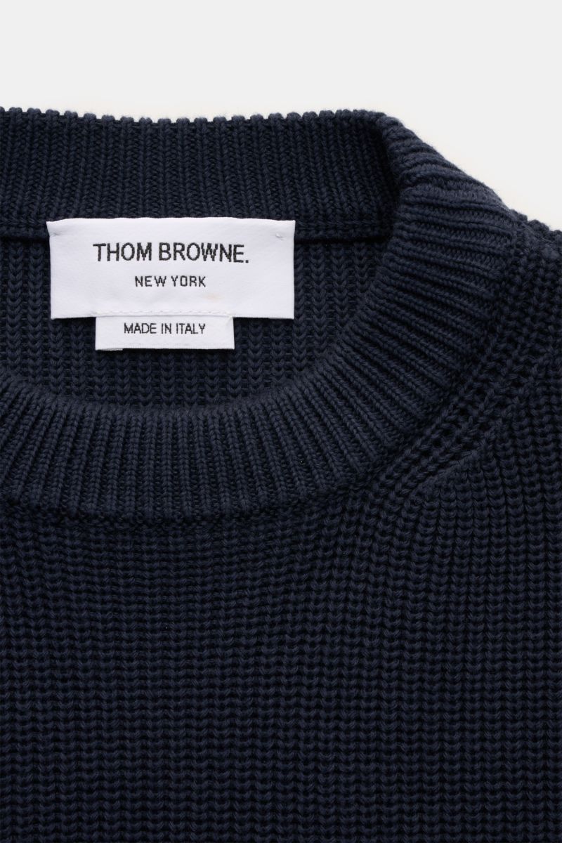 Close-up of the neckline and label of the Thom Browne Rundhalspullover graublau, showing a medium-knit, slim fit cotton crewneck sweater with soft texture, photographed from above. Stilvoll durch die kalte Saison: Der Rundhalspullover aus reiner Baumwolle