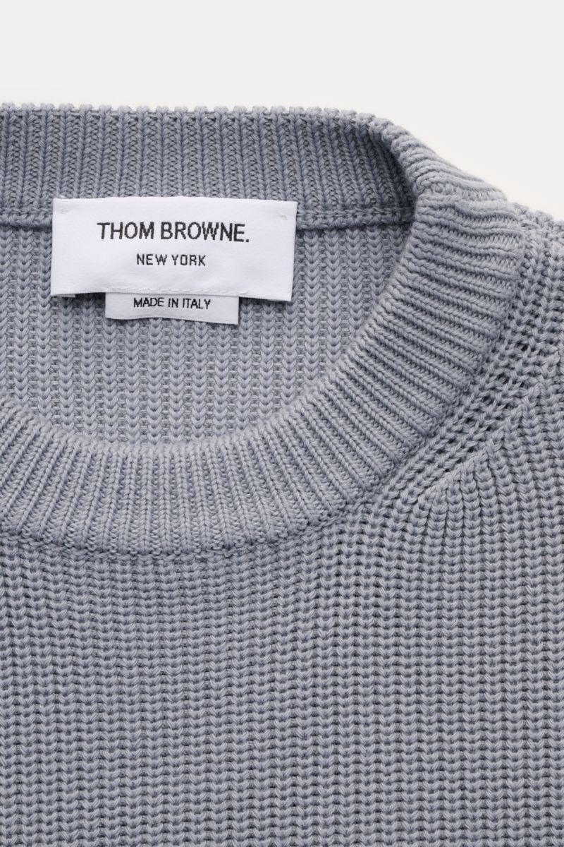 Close-up top-down view of Thom Browne Rundhalspullover rauchblau showing fine medium knit, round neckline, and brand label. Stilvoll durch die kalte Saison: Der Rundhalspullover aus reiner Baumwolle von THOM BROWNE setzt mit seinen charakteristischen Sign