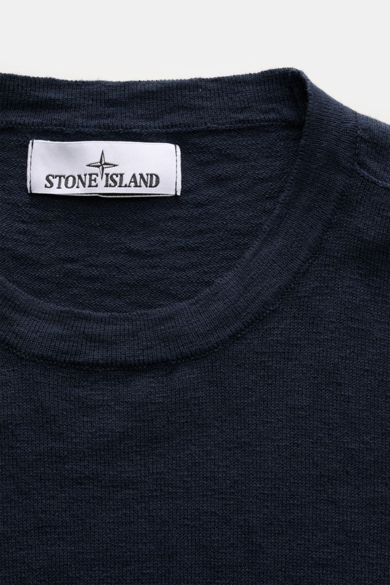 Stone Island Rundhalspullover navy in Slim Fit, aus Baumwoll-Microfaser-Mix mit feinem Strickbild, rolliertem Saum, Nähten und Kompass-Badge, Nahaufnahme von oben.