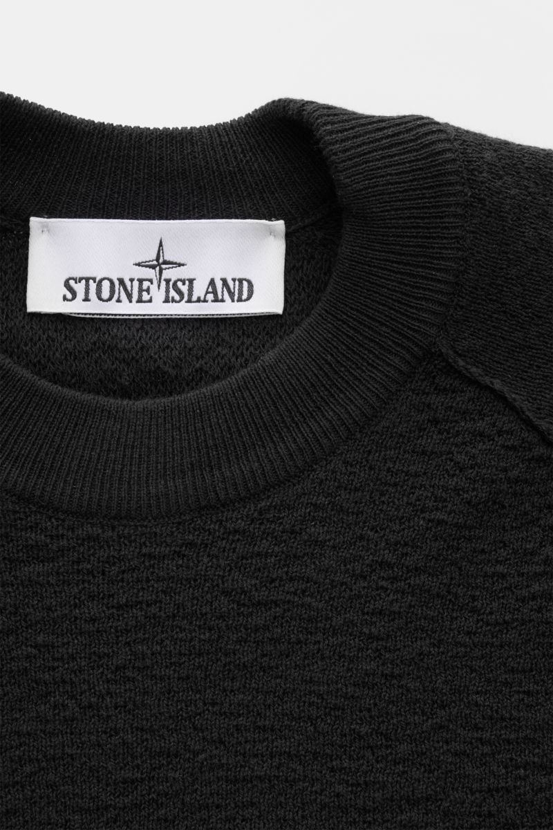 Stone Island Rundhalspullover schwarz, sportiver Strickpullover aus leichter Baumwolle, crincle-Optik, Raglanärmel, Rippbündchen, Detailaufnahme von oben.