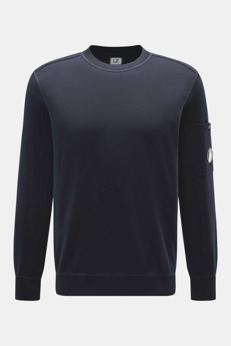 Front view of C.P. Company Crew neck jumper navy in fine knit cotton, featuring a slim fit, ribbed cuffs, and a snap button pocket on the sleeve with signature lens detail. 