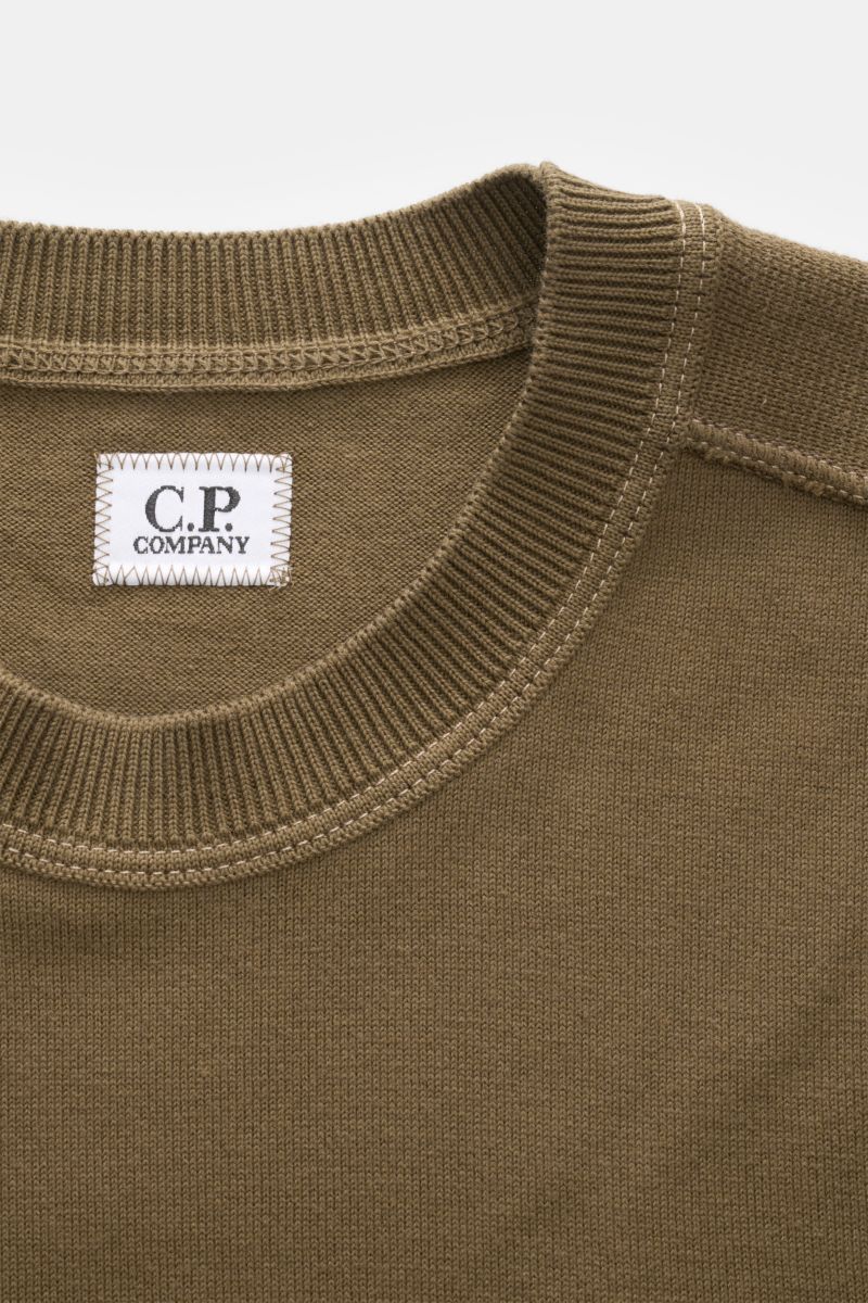 Close-up front view of the C.P. Company Crew neck jumper olive, showing ribbed neckline, fine knit texture, and stitched label inside collar.