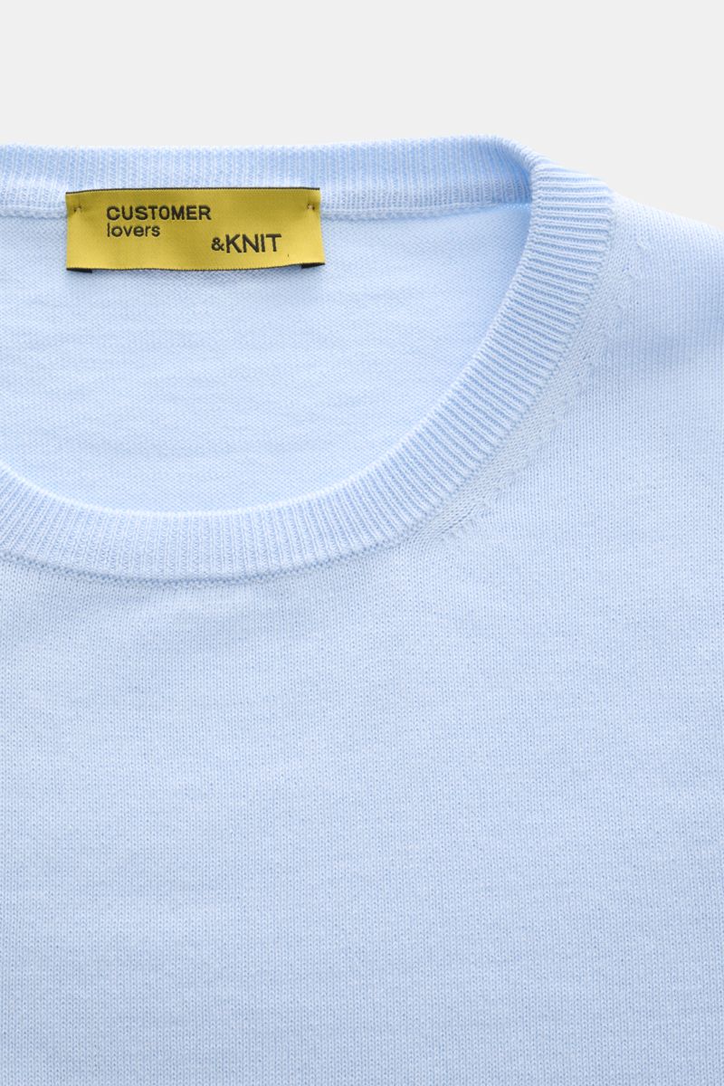 B.F. Knitwear Crew neck jumper light blue shown from a close-up top-down perspective, highlighting the fine knit, soft pure cotton fabric, slim fit, crew neck, and comfortable ribbed bands. A versatile essential for spring with a clean, timeless aesthetic