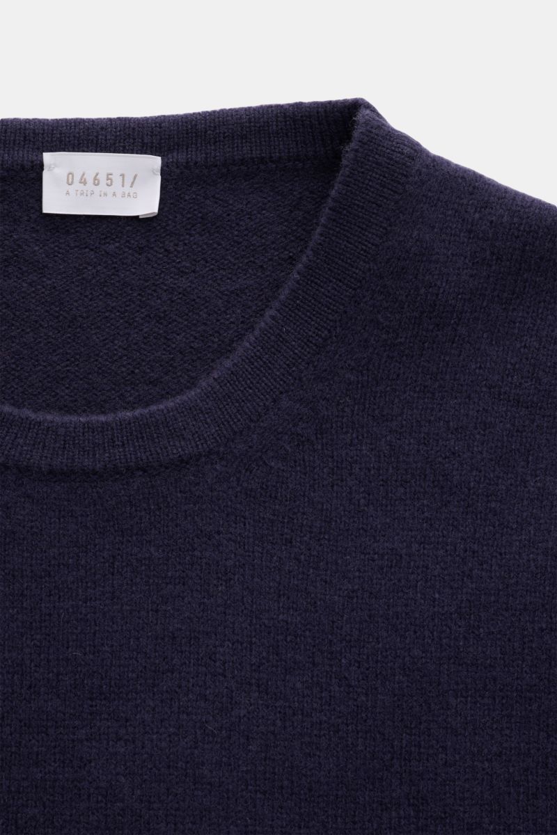 Close-up image of the neckline and upper chest of the 04651/ A trip in a bag Crew neck jumper 'Piping' navy, photographed from above, showing its fine knit, soft wool and cashmere blend with a regular fit, crew neck, and double-layered seams. Cosy and com