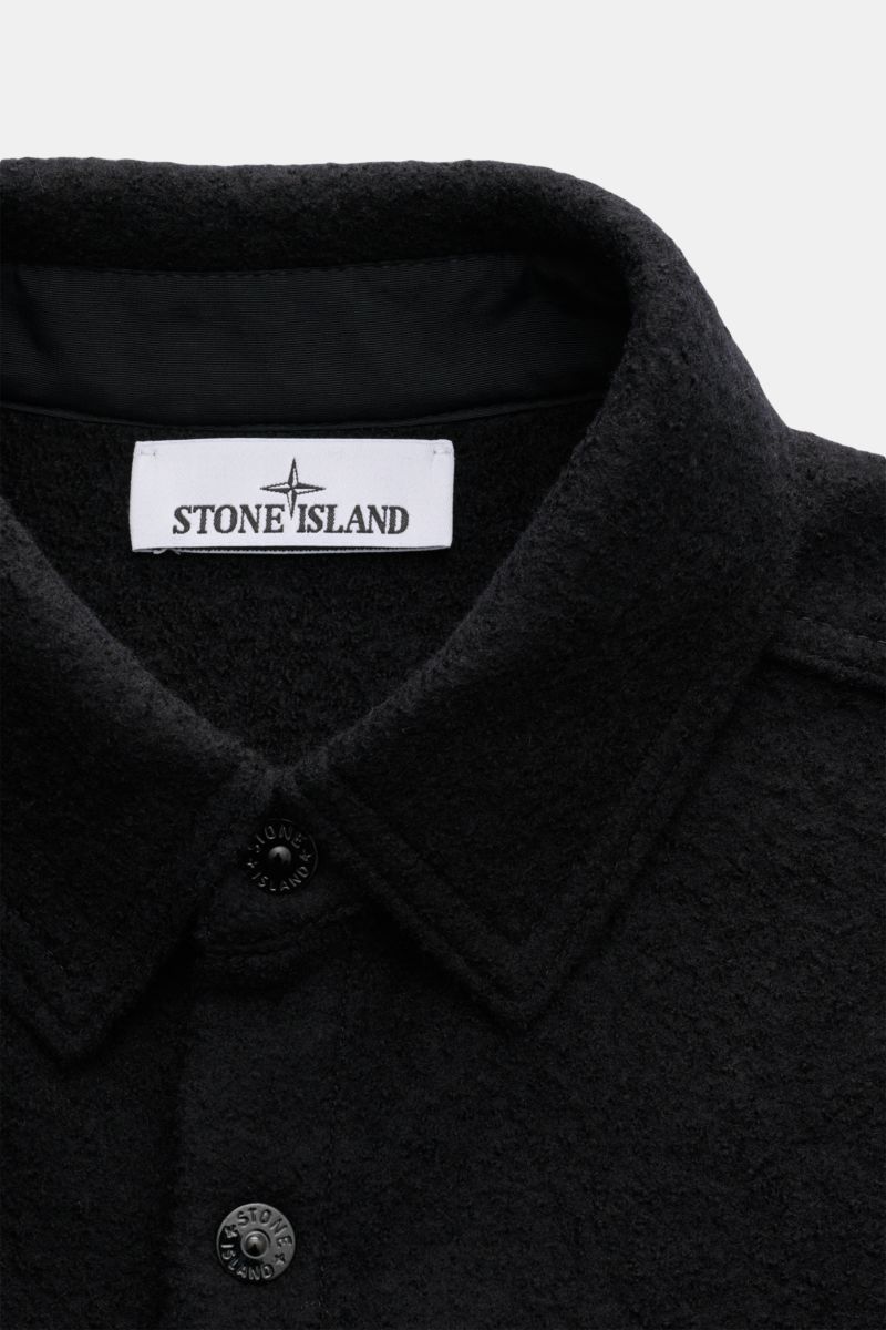 Close-up front view of Stone Island Overshirt schwarz in black, made of reine, gefilzte Wolle with weicher Griff, garment dyed, Regular Fit, Druckknopfleiste, Umlegekragen, aufgesetzte Brusttaschen, and typical Kompass-Badge am Ärmel.