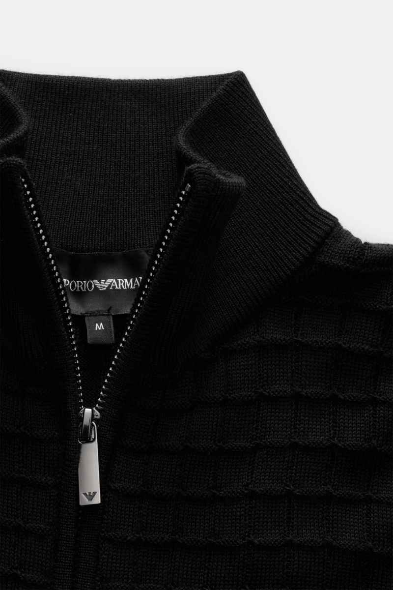 Close-up front view of Emporio Armani Strickjacke schwarz, showing fine knit texture, concealed zipper, tonal logo stitching, and soft ribbed stand collar. Für alle, die dezente Details und stilvolles Design schätzen: Diese Strickjacke von EMPORIO ARMANI 
