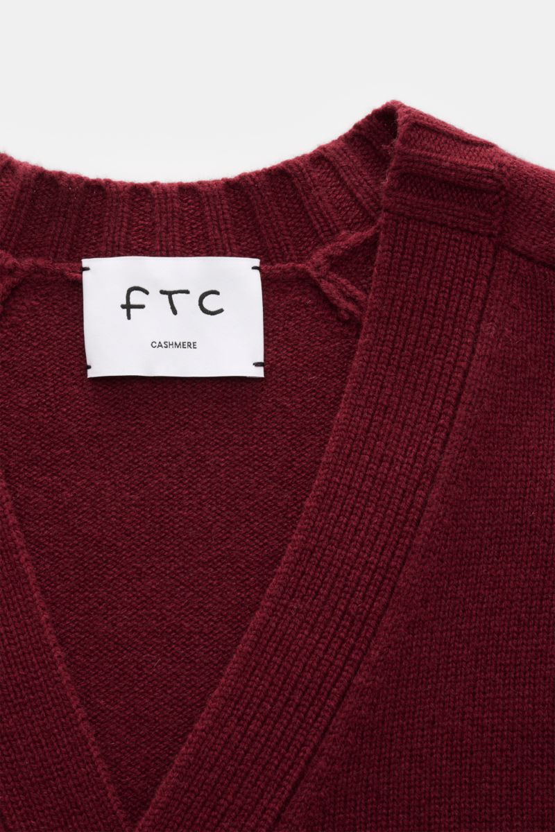 Nahaufnahme des FTC Cashmere Cardigan bordeaux von oben, zeigt V-Ausschnitt, mittelfeines Strickbild und weiches Fair-Trade-Cashmere.