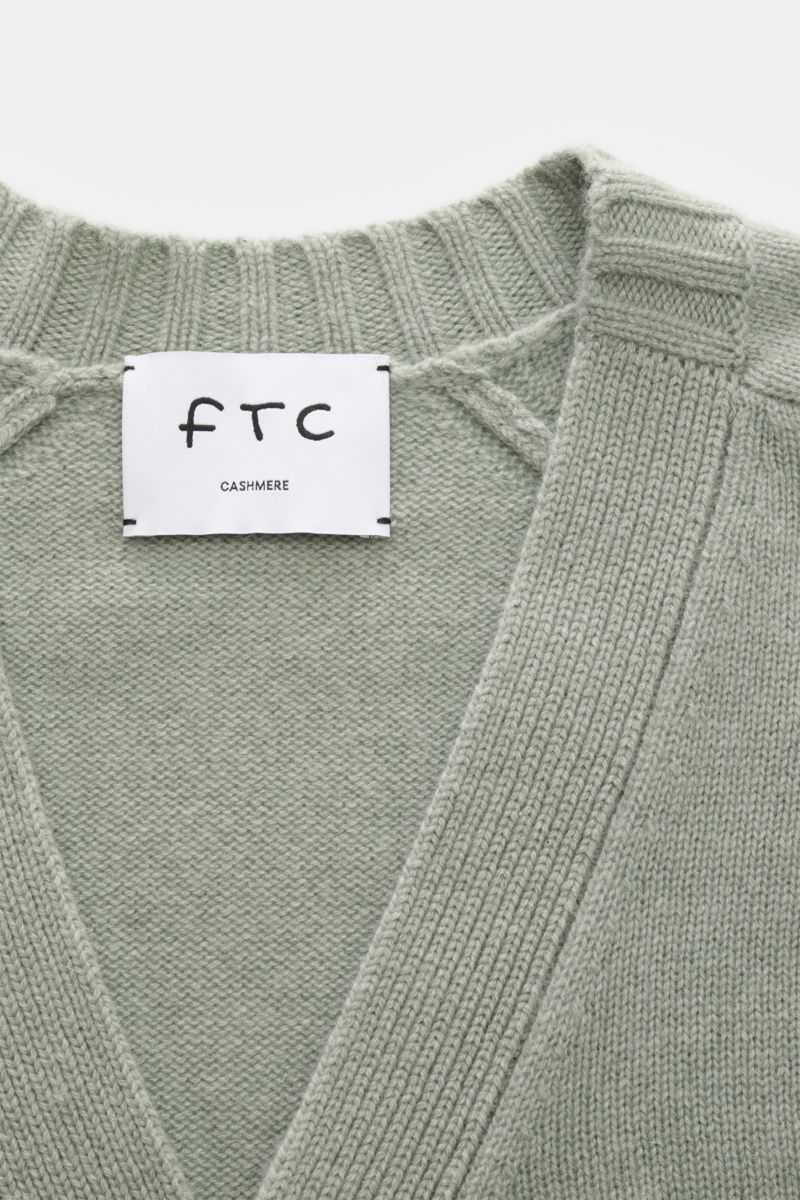 Alt tag (125 characters max):
Close-up front view of FTC Cashmere cardigan grey-green showing V-neck, ribbed bands, and knit texture with label inside collar.

Description:
This luxurious cardigan from sustainable knitwear label FTC is a soft knitted e
