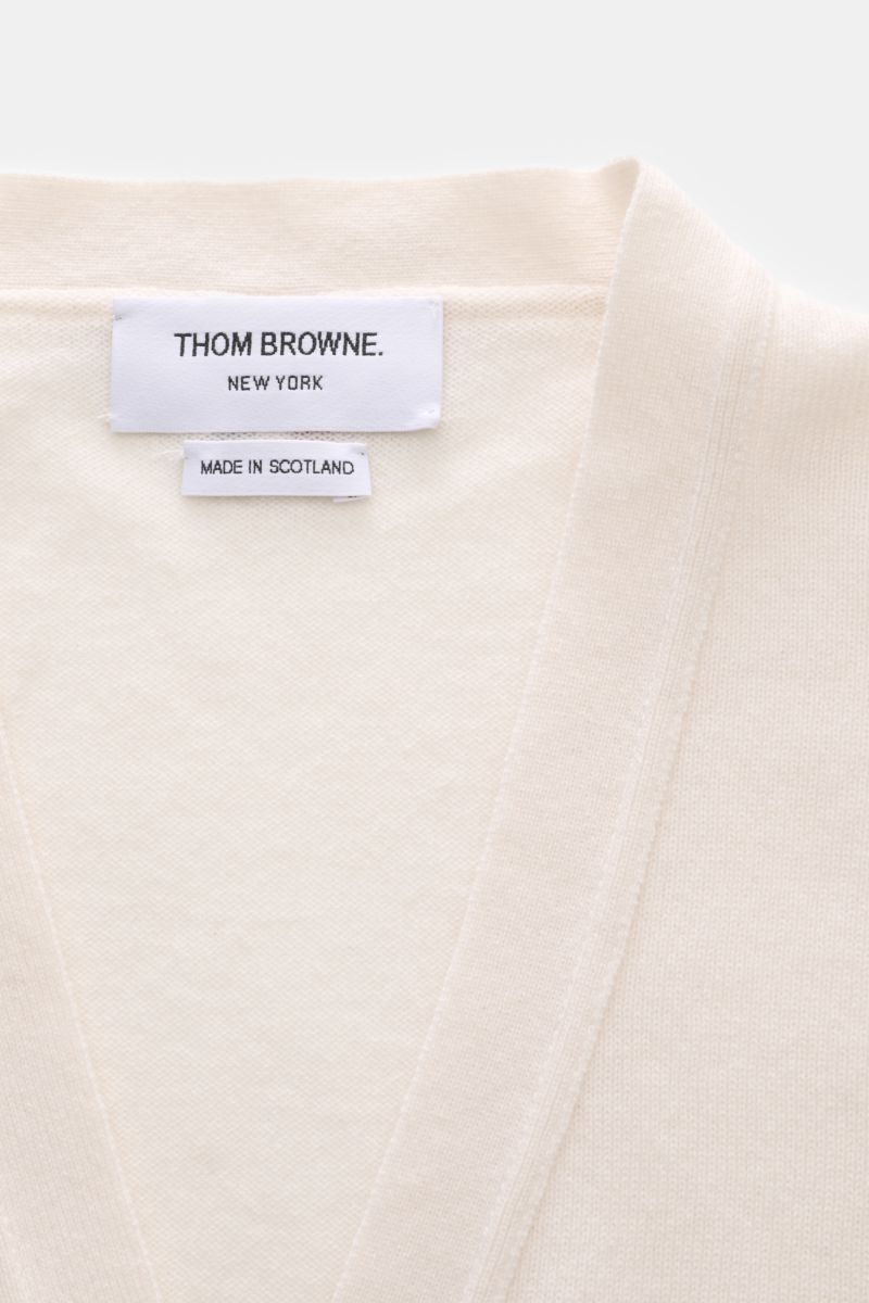Close-up front top view of Thom Browne Cashmere Cardigan offwhite showing pure cashmere fabric, soft texture, fine knit, and neckline with brand label.

Vielseitiger Style-Favorit: Der Cashmere Cardigan von THOM BROWNE kombiniert luxuriöse Materialien 