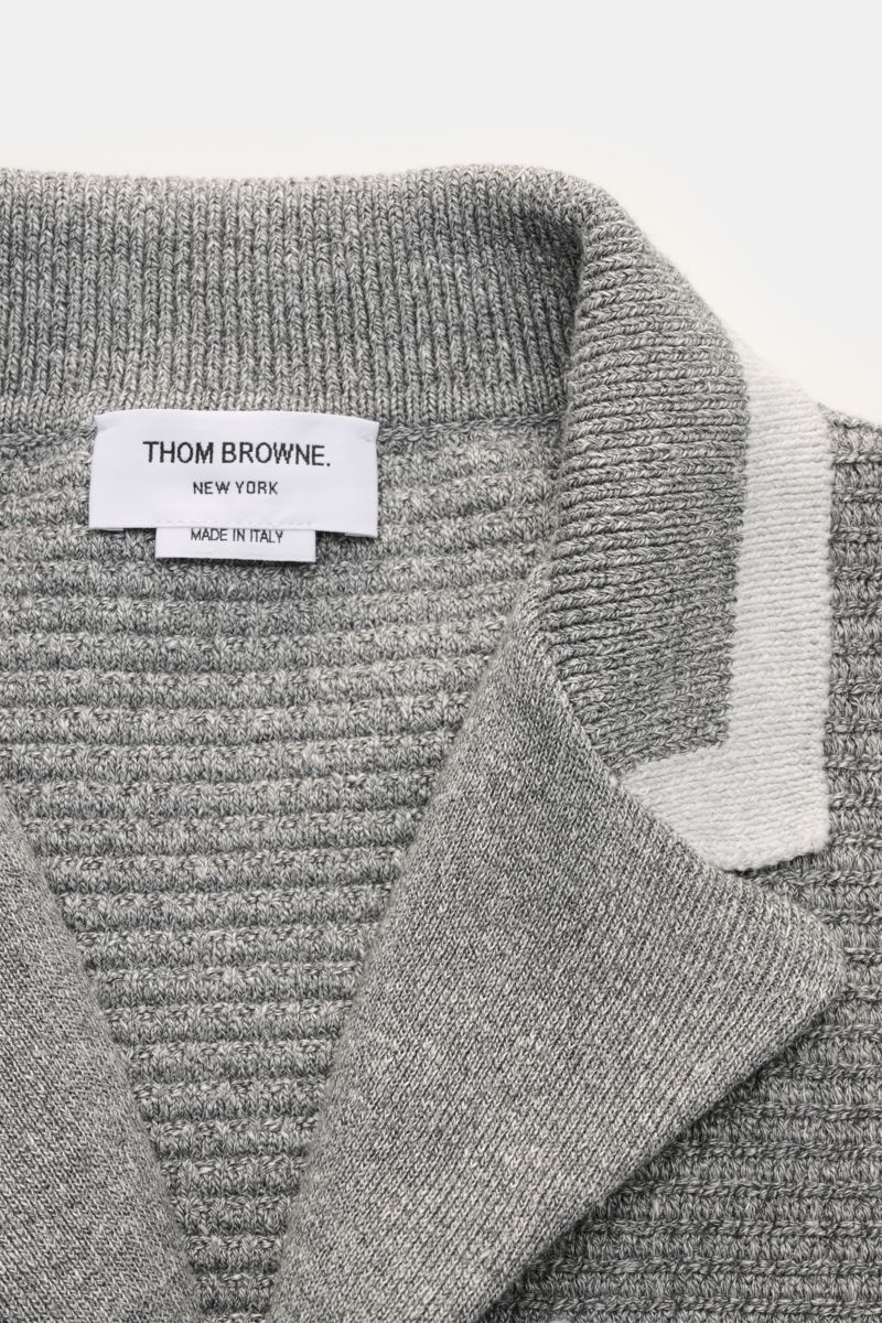 Nahaufnahme von Thom Browne Cardigan hellgrau meliert mit Revers-Ausschnitt, markantem Strickmuster, Tricolore-Ripsband und hochwertigem Leinen-Baumwoll-Mix.