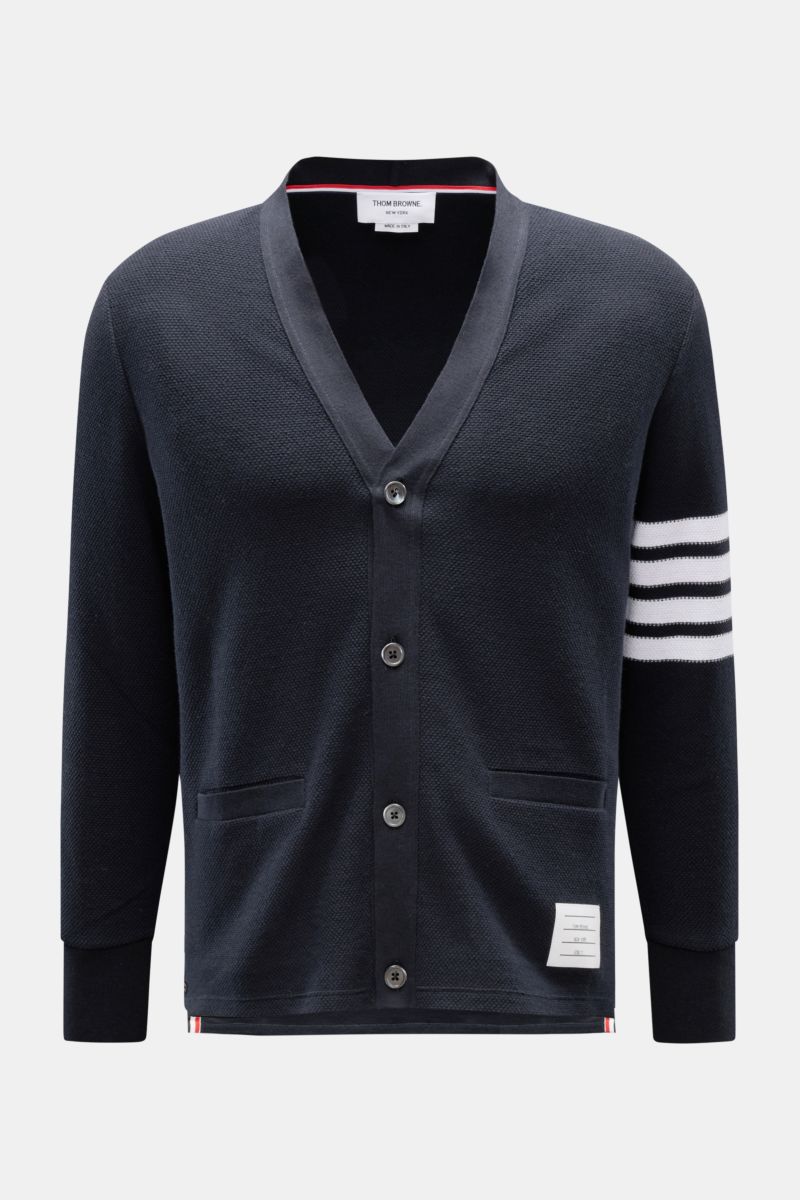 Front view of Thom Browne Cardigan navy, a pure cotton finely textured knit with dark mother-of-pearl buttons, V-neck, hip pockets, tricolour ribbed band, buttoned side vents, contrasting white stripes on sleeve, regular fit, and signature woven label. Th