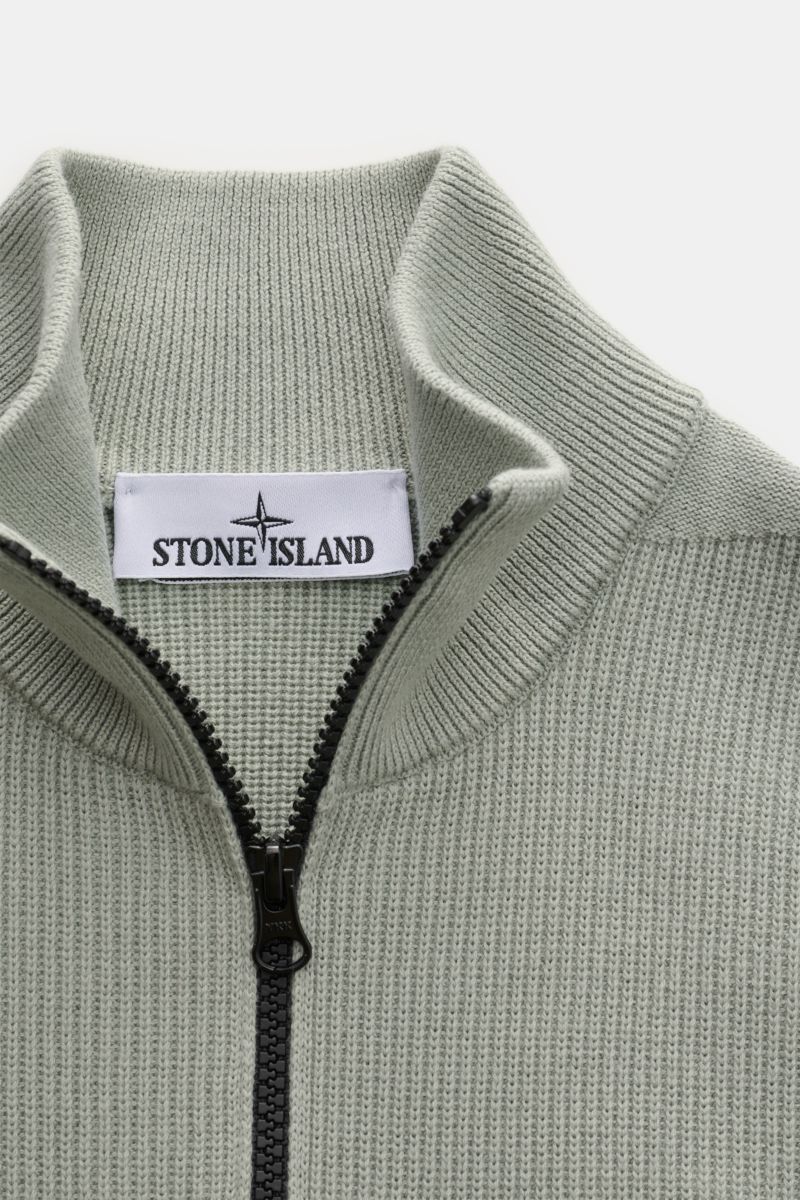 Stone Island Strickjacke 'Rib' salbei shown from close-up front top view, featuring ribbed knit design, soft pure cotton, two-way zipper, standing collar, and Stone Island label inside collar. Zeitloses Layering-Piece: Die Strickjacke von STONE ISLAND wir