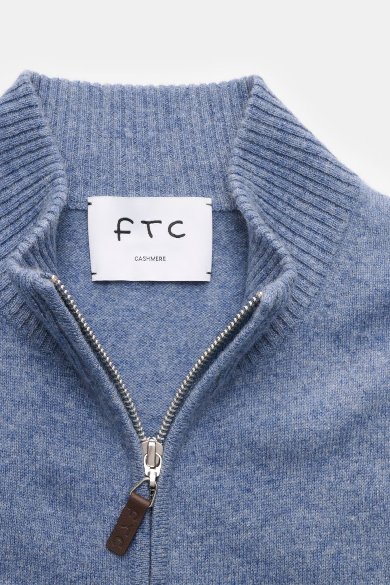 Nahaufnahme der FTC Cashmere Strickjacke rauchblau meliert mit geripptem Stehkragen, verdecktem Zwei-Wege-Reißverschluss und Leder-Logozipper.