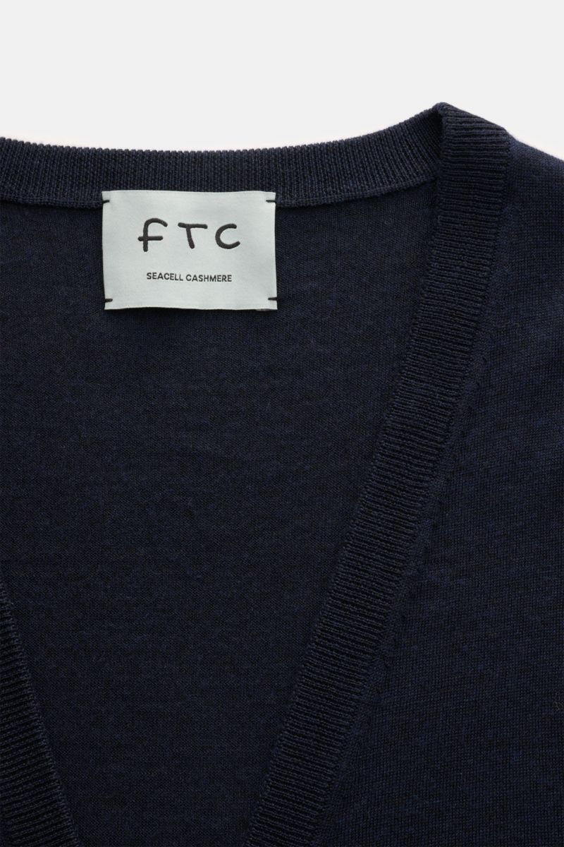 Close-up front view of the FTC Cardigan navy showing the fine knit V-neck and ribbed bands with the FTC label.

This luxurious cardigan by eco-friendly knitwear label FTC is a soft knitwear essential made of fair trade cashmere in a fine blend with Sea