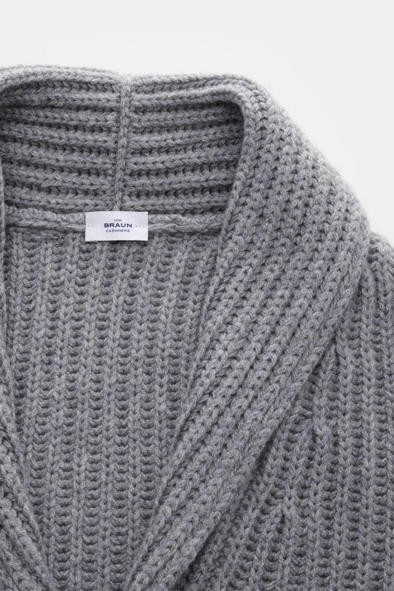 Close-up top-down view of a grey melange von Braun Cashmere cardigan showing its shawl collar, chunky brioche stitch knit, and label. How about a less chunky knit? This cardigan in brioche stitch from the VON BRAUN Cashmere collection is your best defence