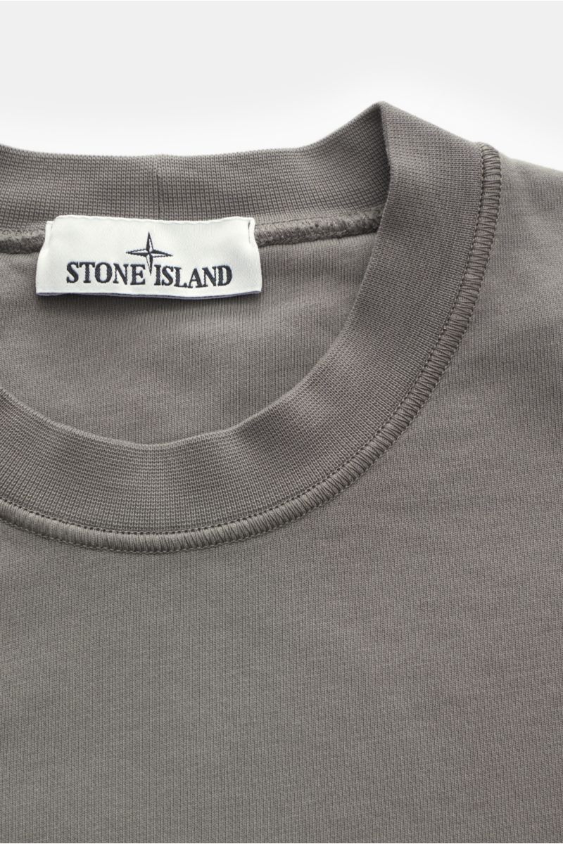 Stone Island Rundhals-Sweatshirt grau, von oben fotografiert, Sweat aus reiner Baumwolle, weicher Griff, markante Nahtverarbeitung, garment dyed, Regular Fit, Rundhalsausschnitt, typisches Kompass-Badge, softe Innenseite, komfortable Rippbündchen.