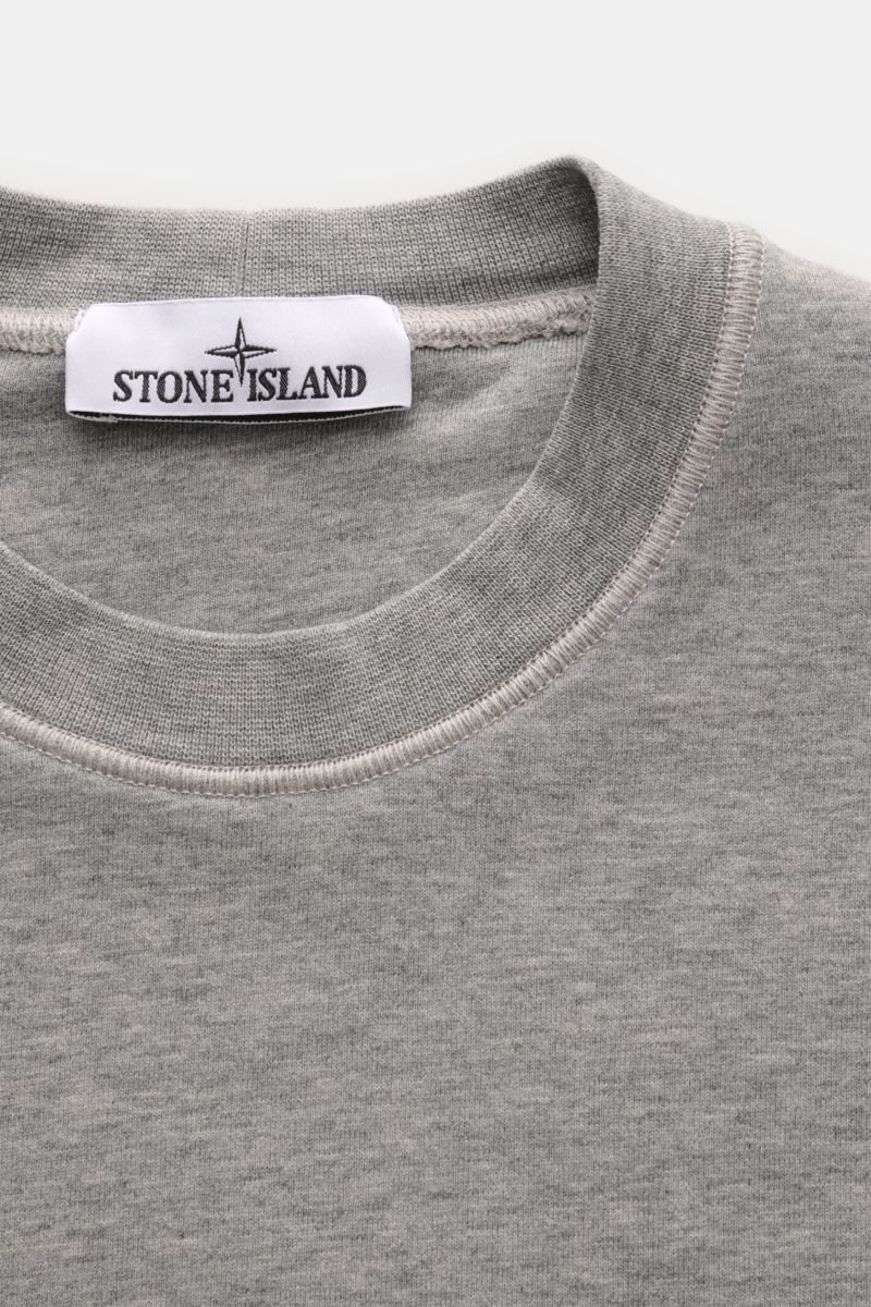 Stone Island Rundhals-Sweatshirt grau meliert, Nahaufnahme von oben, Sweat aus reiner Baumwolle, weicher Griff, markante Nahtverarbeitung, garment dyed, Slim Fit, Rundhalsausschnitt, typisches Kompass-Badge, komfortable Rippbündchen.