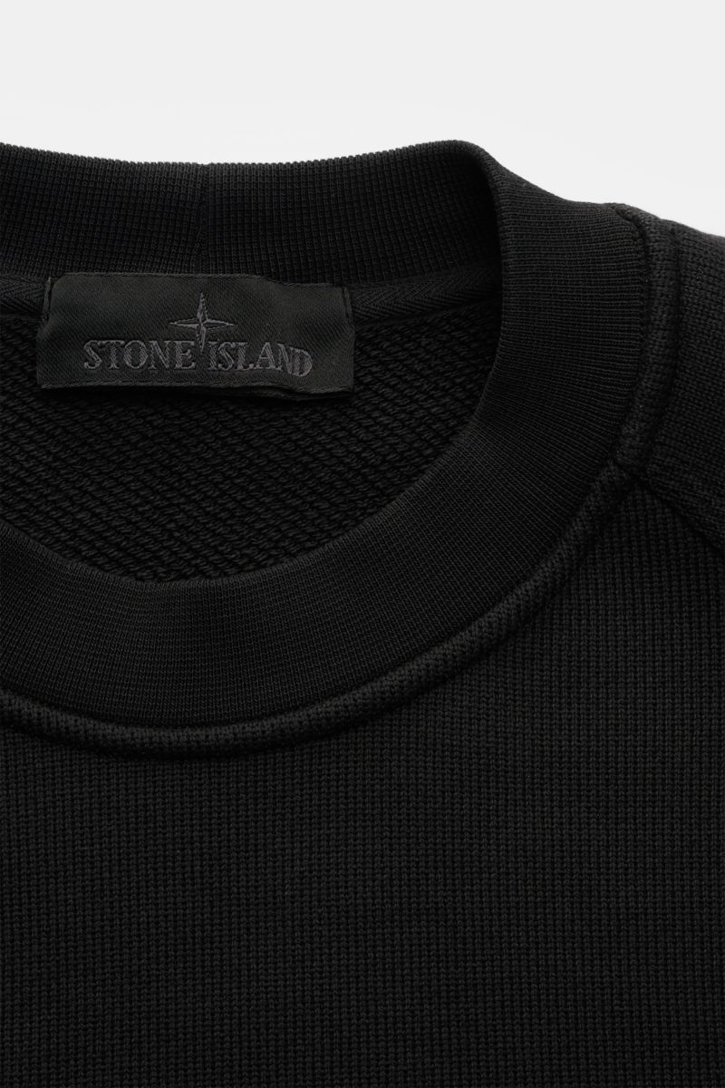 Nahaufnahme des Stone Island Rundhals-Sweatshirt 'Ghost Piece' schwarz, reine Baumwolle, Regular Fit, Raglanärmel, tonales Badge, Rippbündchen.