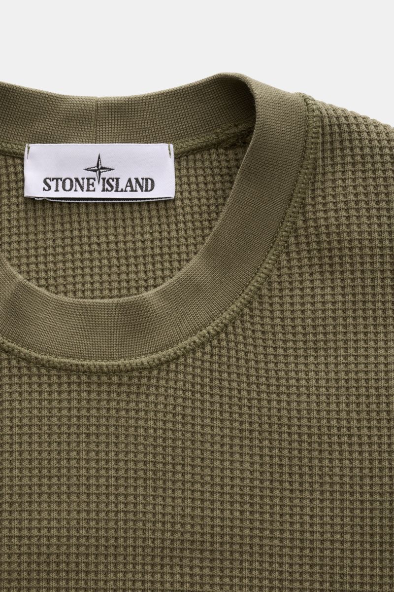 Stone Island Rundhalspullover 'Waffle' oliv shown from a close-up top front view, featuring waffle knit cotton fabric and ribbed crew neck. Basic Piece mit Twist: Dieser Pullover im Waffelstrick von STONE ISLAND wird zur idealen Grundlage moderner Frei