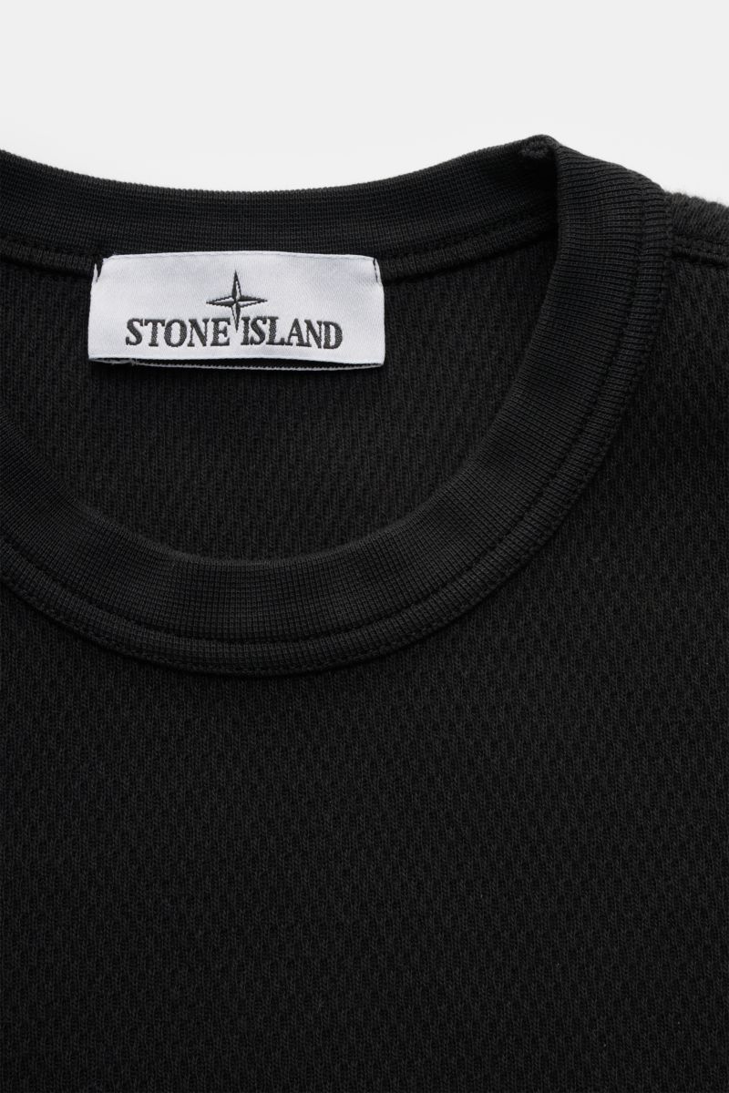 Stone Island Rundhalspullover schwarz, Nahaufnahme von oben, strukturierte Baumwolle, Rundhalsausschnitt, feines Strickbild, Overlock-Nähte sichtbar.