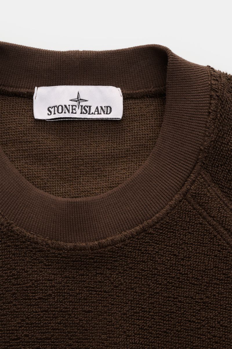 Stone Island Frottee-Rundhals-Sweatshirt dunkelbraun in Nahaufnahme von oben, zeigt schweren Baumwolle-Microfaser-Frottee mit Rundhalsausschnitt und Rippbündchen.
