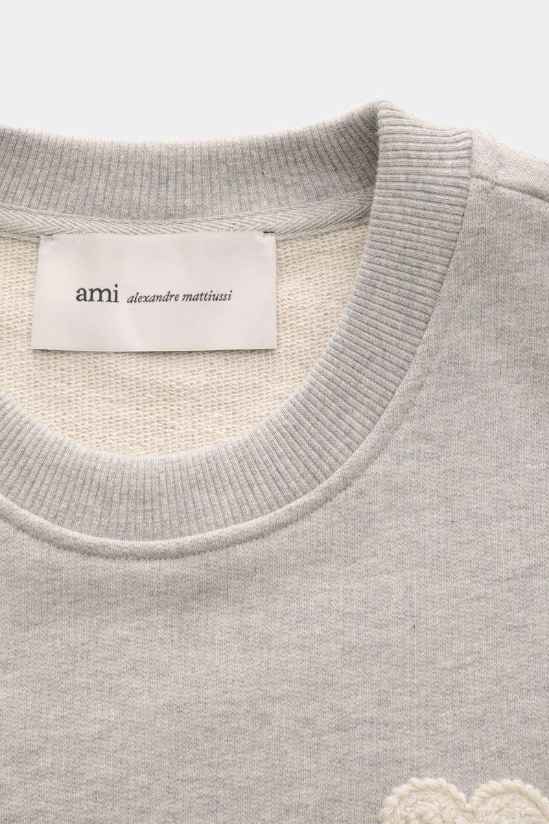 Nahaufnahme des Ami Paris Sweatshirts 'Crewneck' grau meliert von oben, mit Rundhalsausschnitt, Slim Fit, plastischem Herz-Stitching, elastischer Baumwolle und flexiblen Rippbündchen.