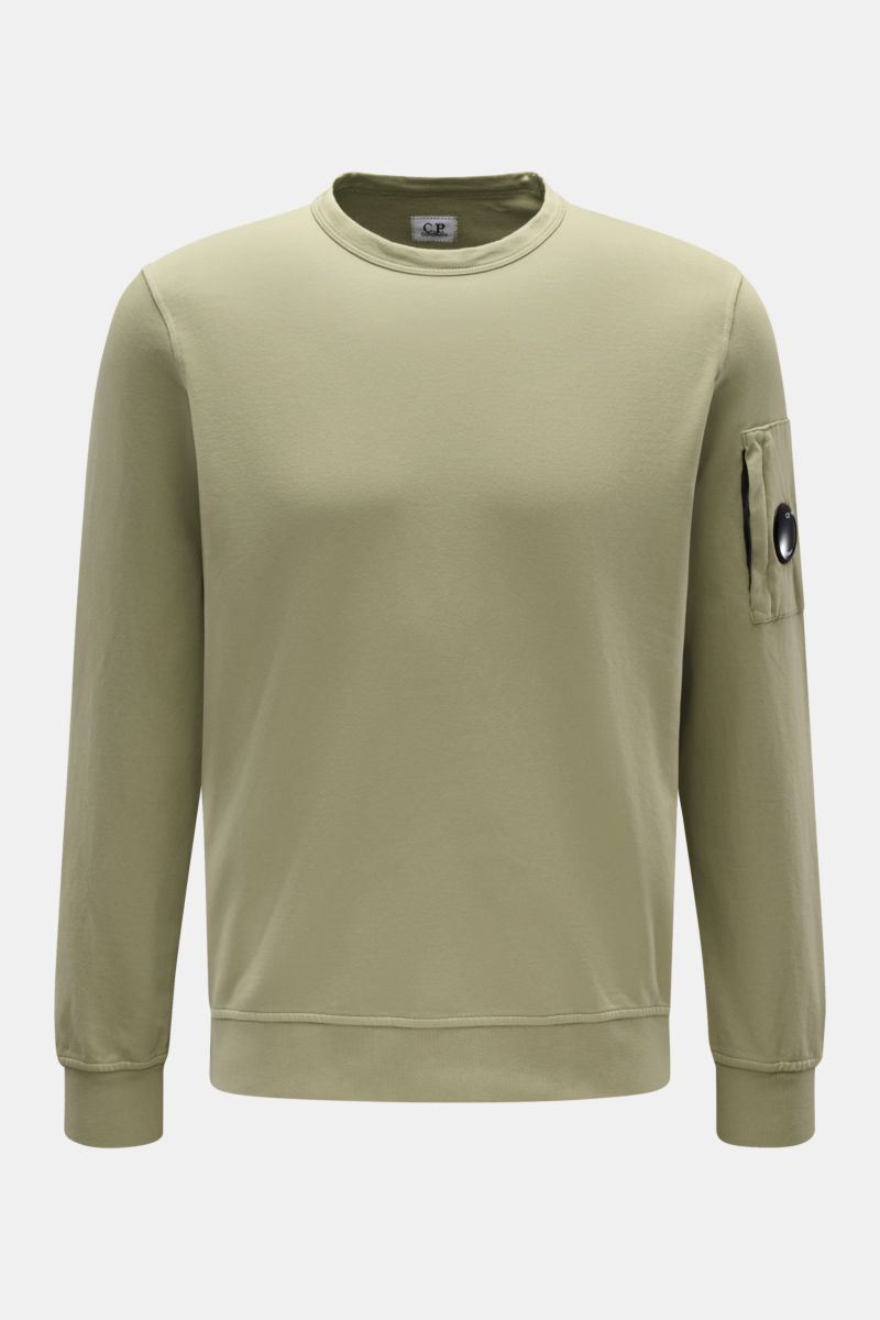 Front view of C.P. Company Sweatshirt oliv in light olive, slim fit round neck with garment dyed cotton, arm zipper pocket with lens detail, ribbed cuffs.