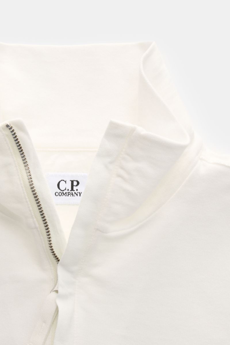 C.P. Company Sweat-Troyer offwhite shown from a close-up top-front perspective, highlighting the half-zip Troyer collar, soft offwhite cotton fabric, and inner brand label. Schon auf den ersten Blick spürt man die sportive DNA: Das innovative Casualwear-L