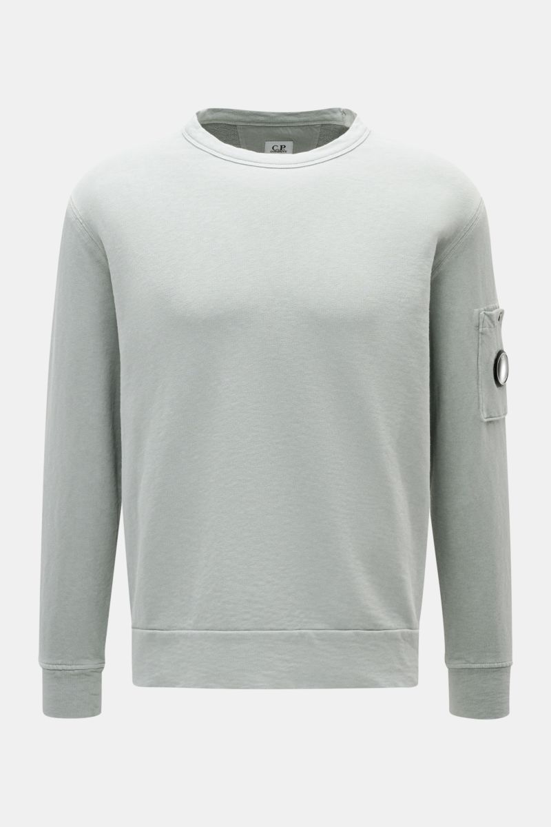 C.P. Company Crew neck sweatshirt grey-green shown from the front, garment-dyed pure cotton with snap button pocket on upper sleeve and signature lens detail 
