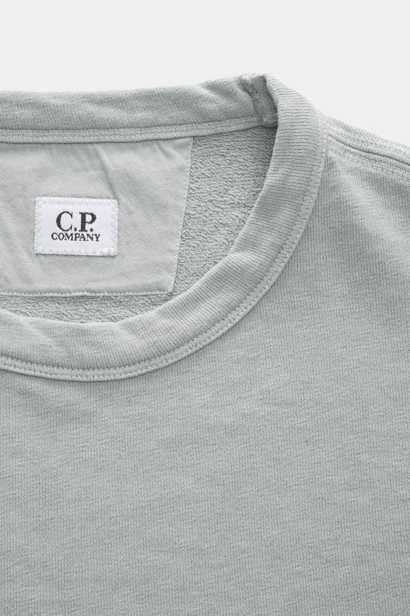 Close-up front view of the collar and inner label of the C.P. Company Crew neck sweatshirt grey-green, featuring lightweight, garment-dyed cotton fabric.

