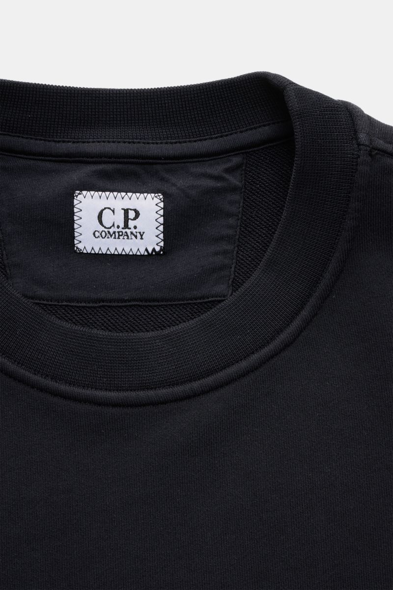 Nahaufnahme des Rundhalsausschnitts und C.P. Company-Labels eines navyfarbenen C.P. Company Sweatshirt navy aus reiner Baumwolle.