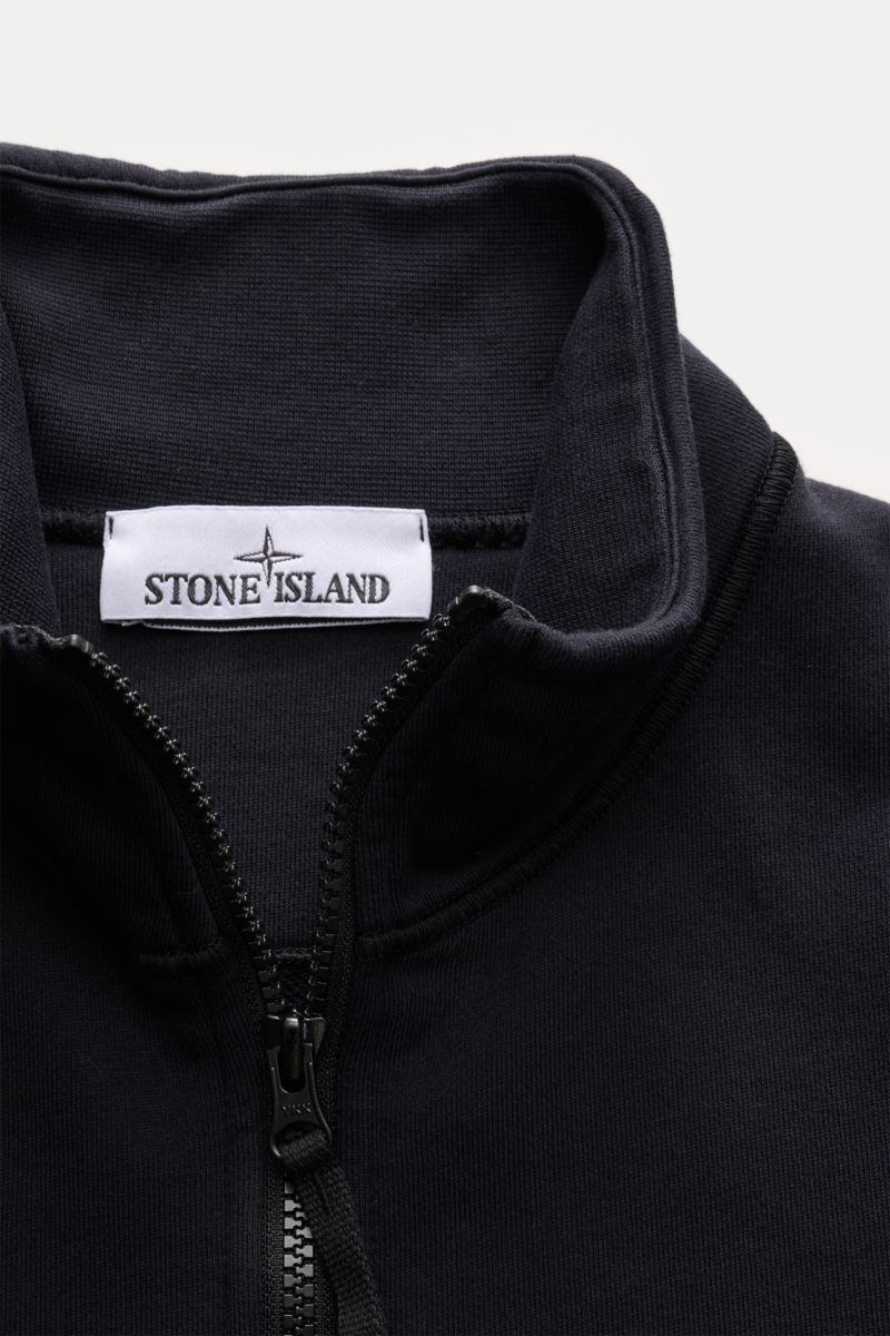 Close-up front view of Stone Island Sweatjacke dark navy showing garment dyed soft cotton fabric, robust zipper, and high stand-up collar with brand label.

Entspanntes Basic von STONE ISLAND: Mit sportiver Lässigkeit begleitet uns die stückgefärbte Sw
