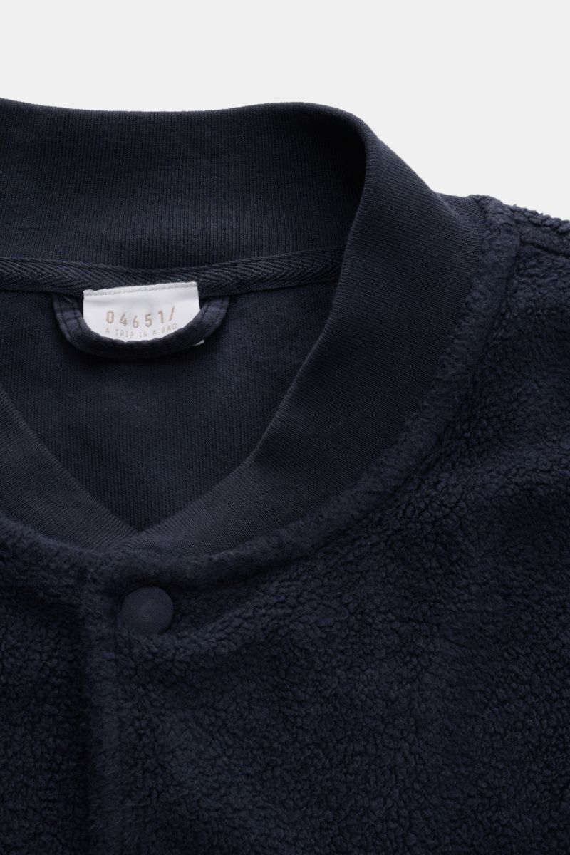 Close-up front view of the navy fleece blouson '04651/ A trip in a bag Fleece blouson navy' featuring pure cotton fleece, soft feel, slim fit, snap button placket, signature rib knit blouson collar, angled hip pockets, comfortable ribbed bands, and woven 