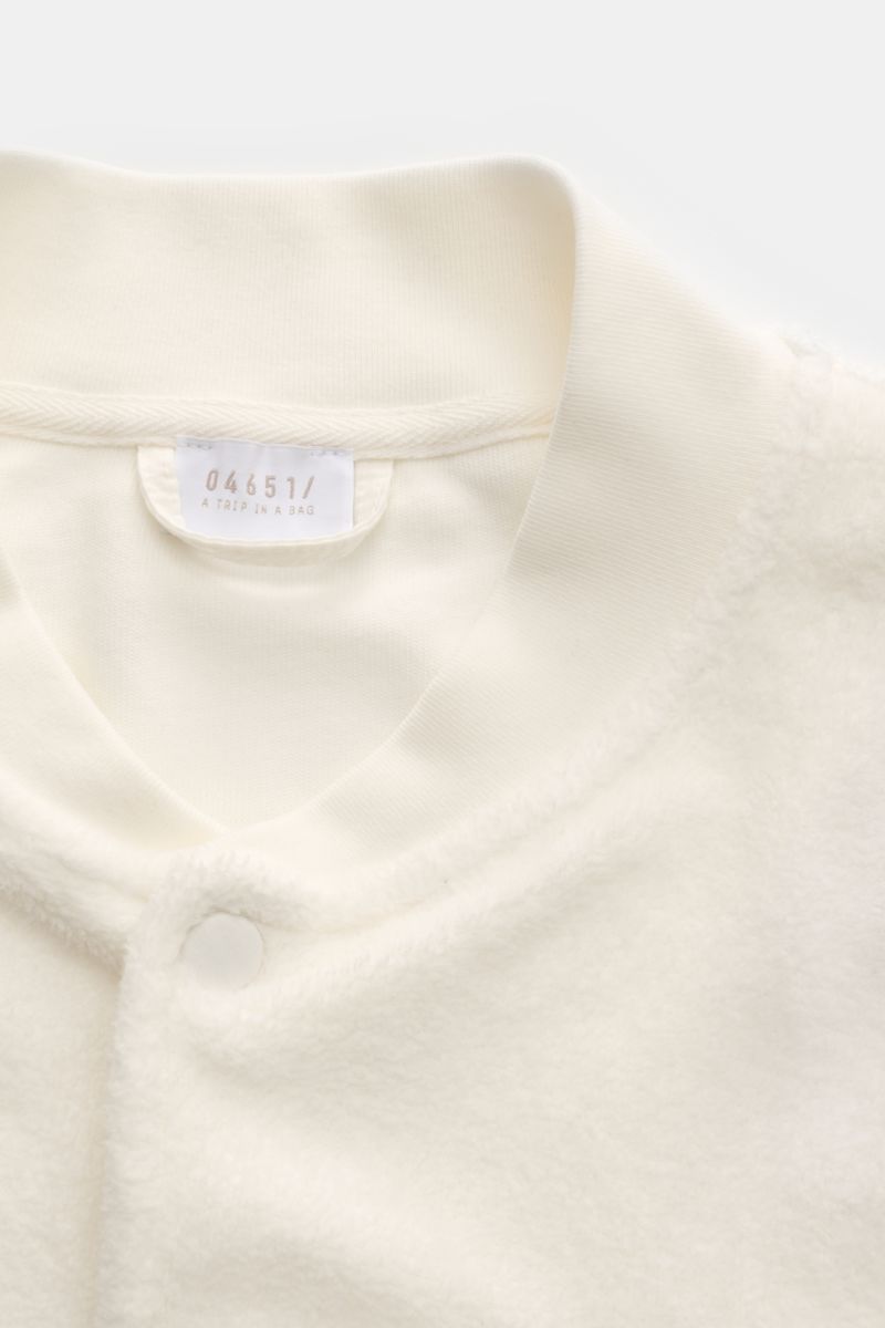 Close-up front view of the 04651/ A trip in a bag Fleece blouson off-white showing pure cotton fleece, soft feel, slim fit, snap button placket, signature blouson collar in rib knit, angled hip pockets, comfortable ribbed bands, and woven label in the sid