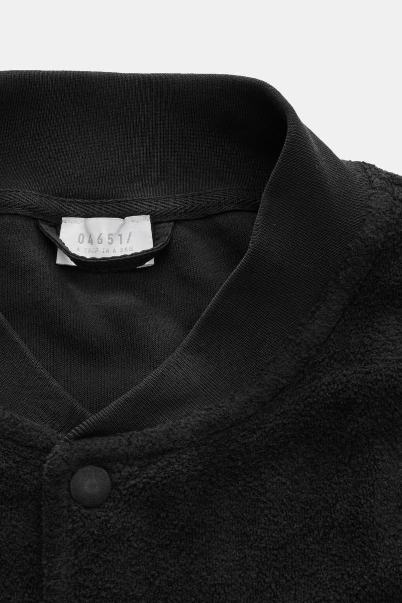Close-up front view of the collar and snap button placket of the 04651/ A trip in a bag Fleece blouson black, made of pure cotton fleece with soft feel, slim fit, signature blouson collar in rib knit, angled hip pockets, comfortable ribbed bands, and a wo