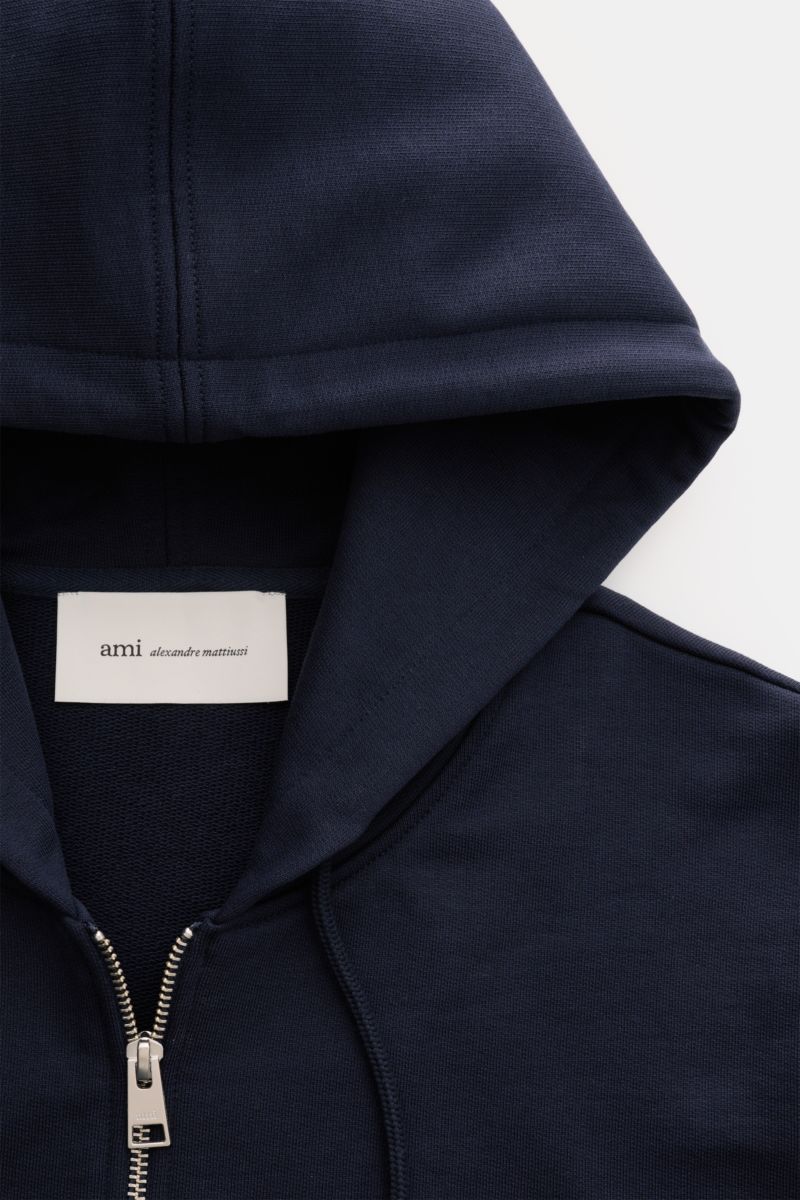 Nahaufnahme der Kapuze und des Zippers der Ami Paris Sweatjacke navy aus Bio-Baumwolle mit Herz-Stitching, Slim Fit, Kängurutasche und Rippbündchen.
