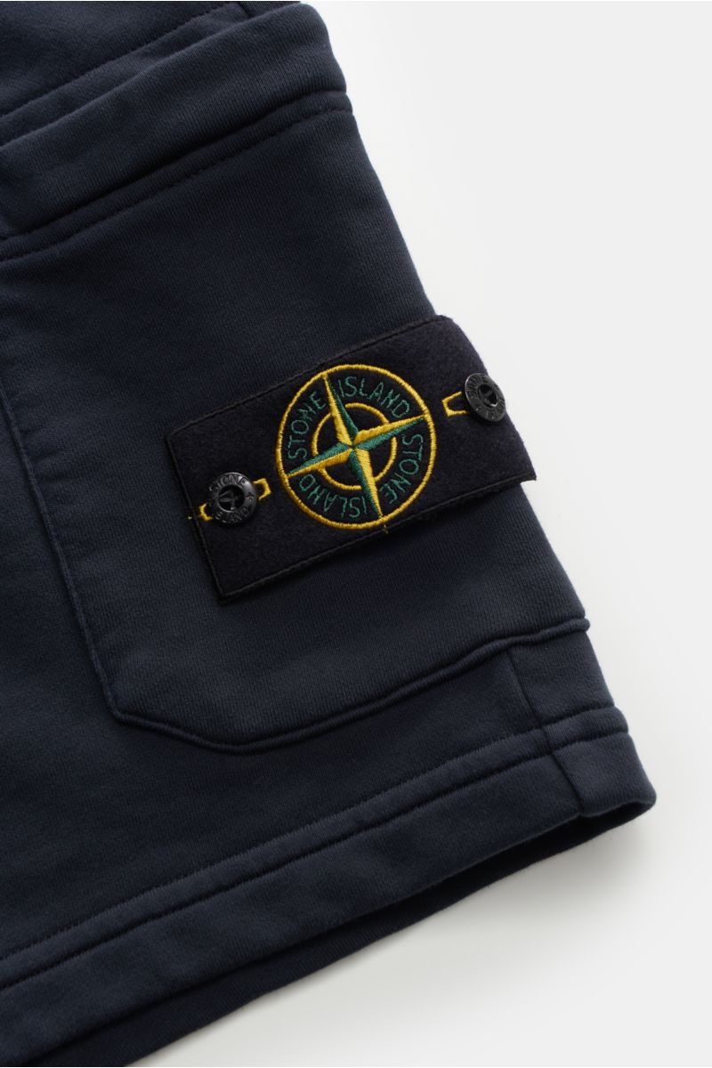 Nahaufnahme der Stone Island Sweatshorts 'Felpa Bermuda' navy von schräg oben, zeigt elastischen Bund, Cargo-Tasche mit Kompass-Badge aus reiner Baumwolle.