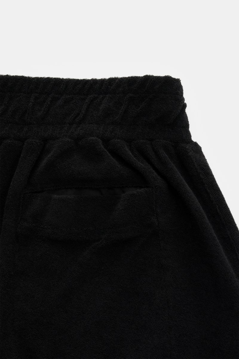 Close-up rear view of the 04651/ A trip in a bag Terry shorts 'Terry' black, showing soft black terrycloth fabric, elastic waistband, and back pocket details. 

With the model 'Terry' 04651/ A TRIP IN A BAG presents a comfortable pair of shorts in wond