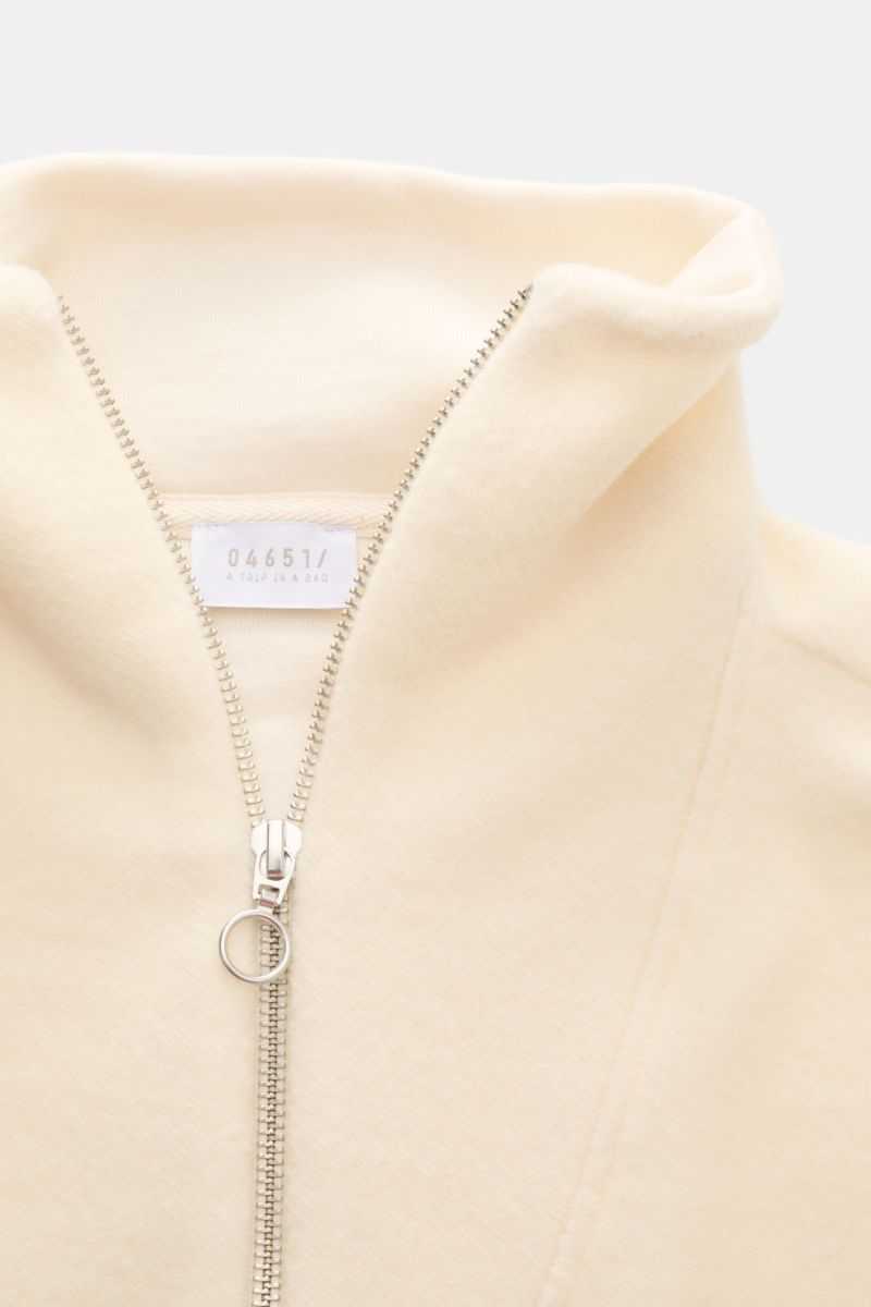 Nahaufnahme des cremefarbenen 04651/ A trip in a bag Troyer 'Cw Quarter Zip' mit Troyer-Kragen, Reißverschluss und weicher Fleece-Textur.