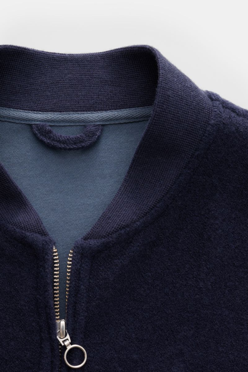 Close-up front view of 04651/ A trip in a bag Blouson dunkelblau with ribbed collar, two-way zipper, and soft wool-cotton fleece texture. Lässig durch die Übergangszeit: Der Blouson von 04651/ A TRIP IN A BAG überzeugt mit seiner samtigen Fleece-Textur au